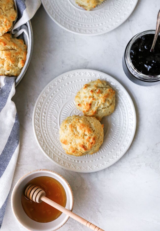 buttermilk biscuits on plate with jar of jam and honey. 